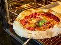 Frisch gebackene Pizza Margherita ohne Backpapier auf einem Ofenrost, mit geschmolzenem Käse und frischem Basilikum.