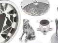 Metalowe wydruki 3D: koło, pies, okrągły element z ażurowym wzorem i części mechaniczne.
