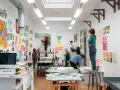 Dans une école d'art animée, des étudiants travaillent sur leurs créations, entourés d'œuvres colorées.