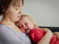 Mama tuli 2-latka, który płacze, przytula go mocno.