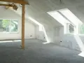 Sottotetto in costruzione con pareti in cartongesso e un pavimento in materiale granulare, pronto per essere calpestabile.