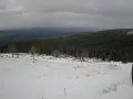 Zimowy krajobraz górski, pokryty śniegiem. W oddali las i mgliste wzgórza. Czy Śnieżka jest otwarta?
