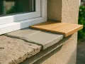 Un appui de fenêtre extérieur en pierre grise avec une nouvelle tablette en bois clair. Idéal pour nettoyer et embellir.