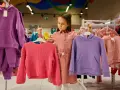 Dziewczynka wybiera ubrania. Czy ten różowy sweterek lub fioletowa bluza to dobry rozmiar dla 7-8 latka?
