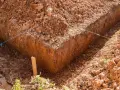 Wykonano wykopy pod fundamenty. Widać głębokie rowy w ziemi, wyznaczone sznurkami.