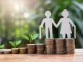 Figuras de papel de ancianos sobre pilas de monedas y brotes verdes. ¿Es sostenible el sistema de pensiones en España?
