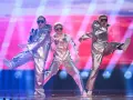Trzech wykonawców w srebrnych strojach i okularach przeciwsłonecznych na scenie. Czy zastanawiasz się, co ile jest Eurowizja?