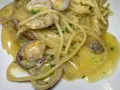 Spaghetti alle vongole cremosi come al ristorante, con vongole fresche e prezzemolo tritato su un letto di pasta dorata.