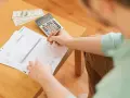 Persona revisa documentos y billetes, calculando cómo hacer un recibo de pago.