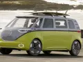 Volkswagen ID. Buzz w kolorze limonkowym z deskami surfingowymi na dachu, nad morzem.