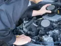 Meccanico che controlla il debimetro auto, un componente essenziale per il corretto funzionamento del motore.