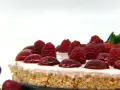 Cheesecake senza gelatina, guarnita con lamponi succosi e ciliegie lucide, su una base croccante.