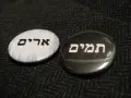 Two round pins with Hebrew text: "Urim" on a white background and "Thummim" on a black background.