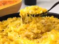 Risotto cremoso de calabaza en un plato, con una cuchara sacando una porción.