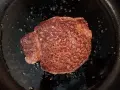 Ein saftiges Steak brutzelt in der Pfanne, bestreut mit grobem Salz.