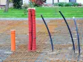 Przygotowania do wylania płyty fundamentowej: zbrojenie, rura pomarańczowa i czerwone peszle z kablami.