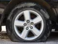 Ruota sgonfia dell'auto, con cerchione in lega a cinque razze e pneumatico sporco.