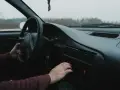 Dłoń kierowcy reguluje radio samochodowe.