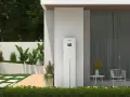 Biały magazyn energii 5 kW, stojący przy nowoczesnym domu, z zielenią i tarasem. Zastanawiasz się, na ile wystarczy taki magazyn energii?