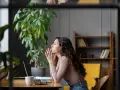 Mujer pensativa en su escritorio, con las manos juntas, reflexionando sobre sus permisos retribuidos.