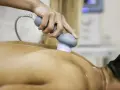 Physiotherapeutin behandelt Rückenschmerzen mit Ultraschall. Die Behandlung lindert Schmerzen nach Verletzungen.