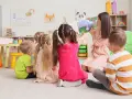 Nauczycielka czyta dzieciom bajkę. W przedszkolu bezpłatnych godzin jest 5.