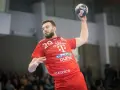 Piłkarz ręczny Nedim Remili w czerwonej koszulce z numerem 29, z piłką w dłoni, gotowy do rzutu.