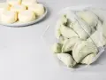Mrożone pierogi w woreczku obok talerza z okrągłymi serkami.