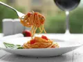 Widok na talerz spaghetti z sosem pomidorowym i listkiem bazylii. Widelec podnosi porcję makaronu. Idealne pytanie: jakie wino do bolognese?