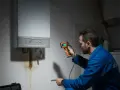 Tecnico esamina una caldaia con termocamera, notando una perdita. La pressione della caldaia è di 3 bar.