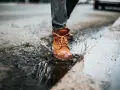 Botas de cuero marrón salpican un charco, demostrando que el cuero es impermeable.