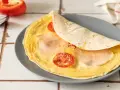 Pyszna tortilla z jajkiem, pomidorem i szynką, gotowa do zjedzenia.