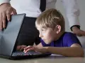 Chłopiec pochłonięty grą na laptopie, a dorosły próbuje pomóc w leczeniu uzależnienia od komputera.