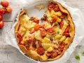 Torta salata estiva con patate, pomodorini e formaggio filante, un tripudio di sapori mediterranei.