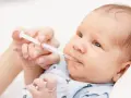 Rączka podaje noworodkowi strzykawkę z płynem. To ważna witamina K dla noworodka, zapewniająca mu zdrowy start.