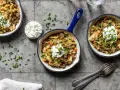 Herzhafte spitzkohl hack pfanne mit einem Klecks Sauerrahm und Schnittlauch garniert, serviert in kleinen Gusseisenpfannen.