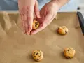 Hände formen Teig für einen Skillet Cookie mit Schokoladenstückchen auf Backpapier.