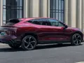 Czerwony luksusowy SUV Denza N9 widziany z boku, na tle budynku z kolumnami.