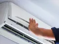 Ręka technika otwiera obudowę klimatyzatora do sprawdzenia szczelności.