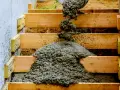 Vertido de hormigón en modernas escaleras exteriores de obra, con encofrado de madera y pared de hormigón.