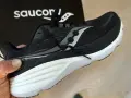 En svart Saucony löparsko, modell Guide 24, hålls upp. Denna sko är designad för att ge stöd och stabilitet, vilket är viktigt för att förstå vad pronation betyder för löpare.