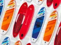 Bunte SUP-Boards, auch Stand-Up-Paddleboards genannt, liegen nebeneinander. Sie sind für Wassersportler gedacht.