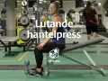 Kvinna förbereder sig för lutande hantelpress på gym. En hantel ligger bredvid henne.