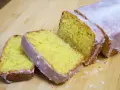 Un delicioso pastel de limón, cubierto con glaseado blanco, cortado en rebanadas sobre una tabla de madera.