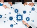 A diverse group of people gather around a table, their hands pointing to an AI diagram. This ai board of directors is strategizing the future of artificial intelligence.