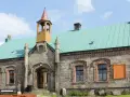 Kamienny budynek z turkusowym dachem i wieżyczką. To schronisko Orle, malowniczo położone wśród drzew.