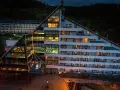 Nowoczesny hotel Klimczok Resort & Spa nocą, z oświetlonymi oknami i wejściem. Wiele pozytywnych hotel klimczok resort & spa opinie potwierdza jego urok.