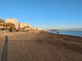 Plaża w Albanii, z palmami i budynkami w tle, idealna na spacer. Klimat sprzyja relaksowi nad morzem.