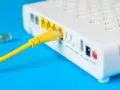 Żółty kabel sieciowy podłączony do portu LAN routera i modemu.