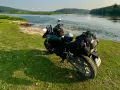 Motocykl z bagażem nad rzeką, gotowy do podróży po Litwie. Przepisy drogowe to podstawa bezpiecznej wyprawy.